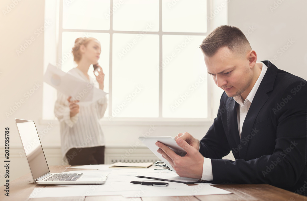Male and female managers working on financial papers at modern office interior Male and female managers working on financial papers at modern office interior