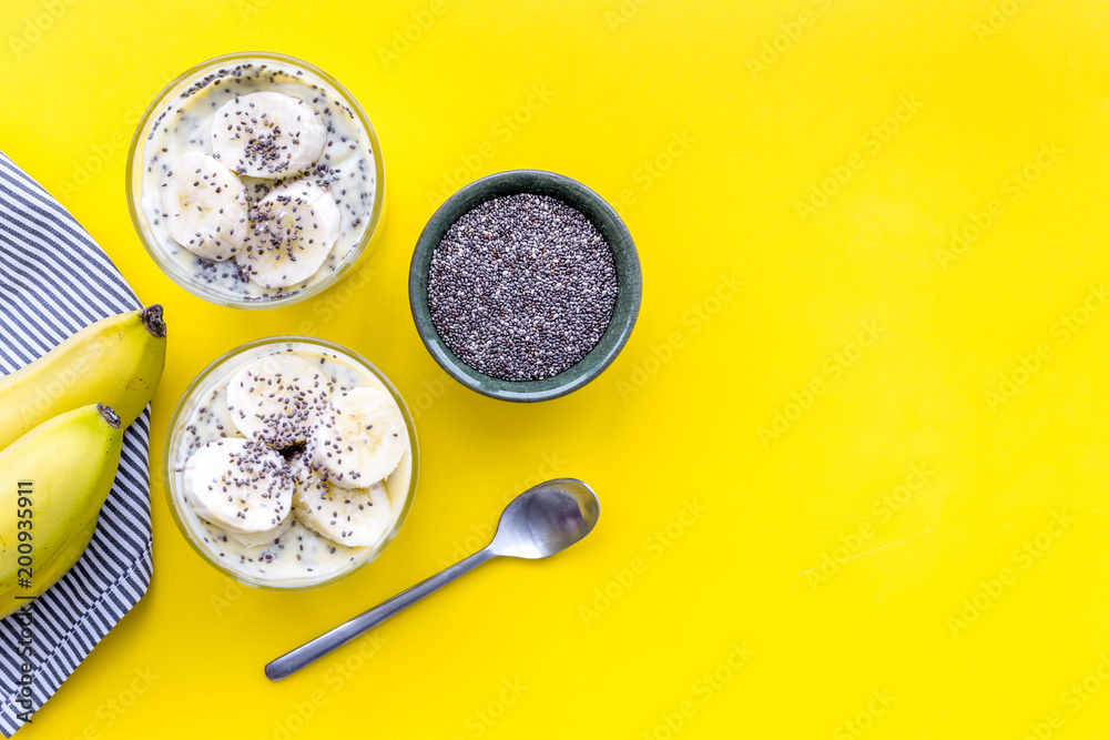 Idea for healthy breakfast. Banana pudding with chia seeds on yellow table with blue tablecloth top view copy space