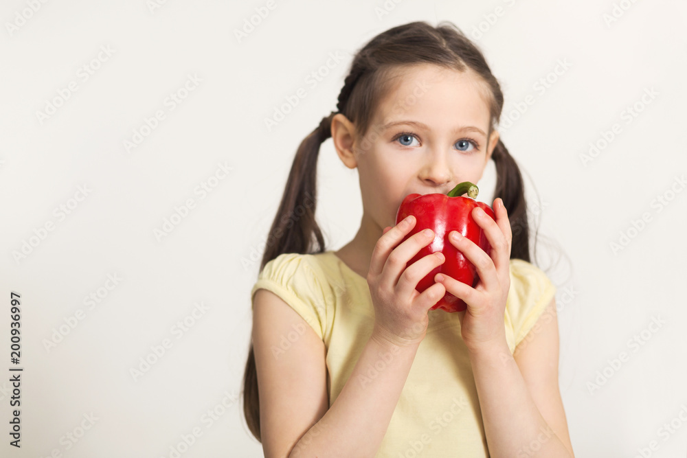 Pretty cute little girl biting bell pepper over white background Pretty cute little girl biting bell pepper over white background