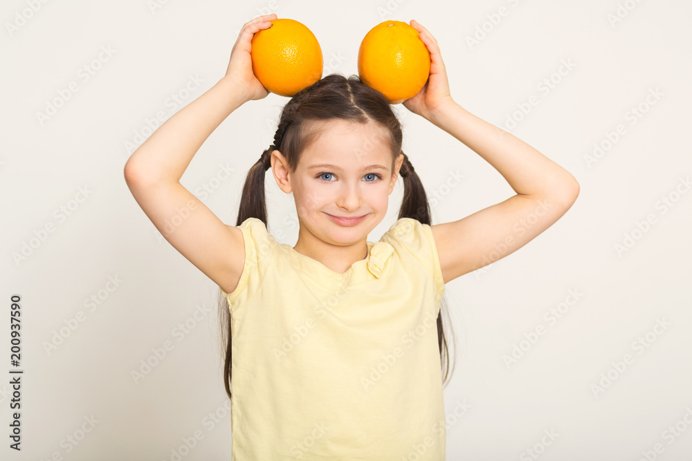 Happy little girl having fun with oranges over white background Happy little girl having fun with oranges over white background