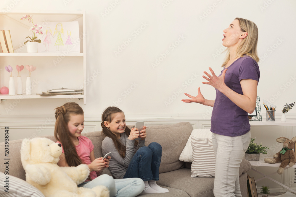 Mother feeling angry while little girls using mobile phones Mother feeling angry while little girls using mobile phones