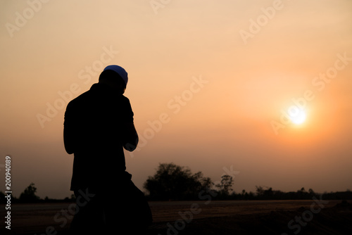 Canvas Print Silhouette Young asian muslim man praying on sunset,Ramadan festival concept