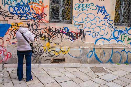 Foto Persona che guarda un muro esterno di un’abitazione imbrattato da scritte