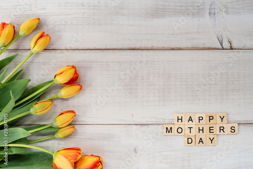 Yellow and red tulips on whitewashed wood with Mother's Day message