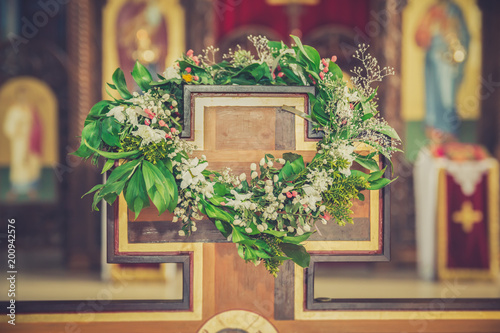 Wreath made of colorful flowers hanging on a wooden cross in church. Vintage style photo. photo