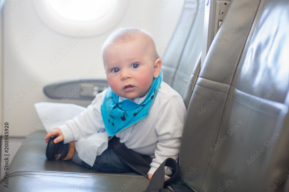 Cute little baby boy, playing with toys on board of aircraft Cute little baby boy, playing with toys on board of aircraft