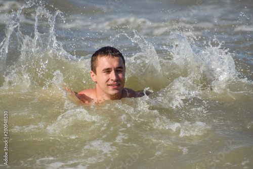 Athletic man in sea water. Bathing in the sea. A man is swimming among the waves of the sea © eleonimages