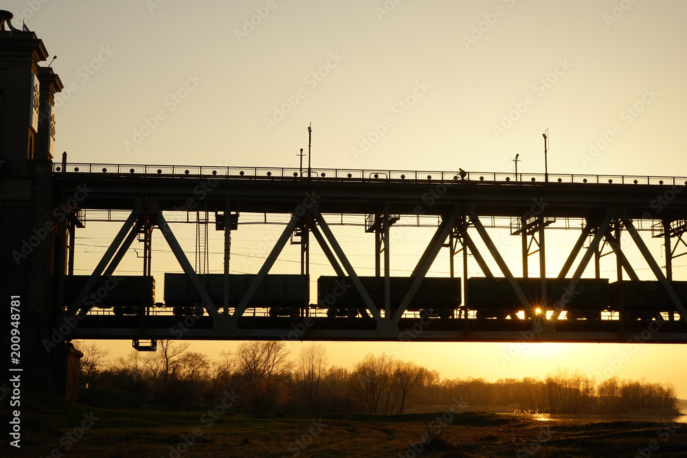 Fototapeta premium sun, sunset, bridge, river, shore, growth, orange, industry, wagons,spring