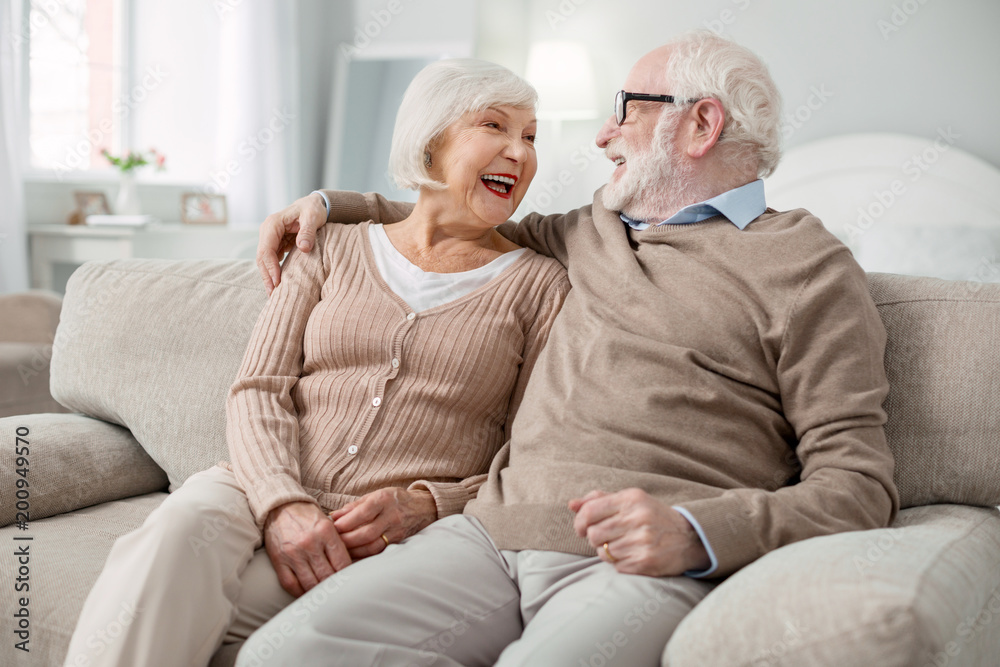 Happy together. Joyful elderly couple smiling to each other while being in a great mood Happy together. Joyful elderly couple smiling to each other while being in a great mood