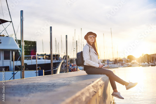 Pretty young woman in black hat with vape at a sea port photo