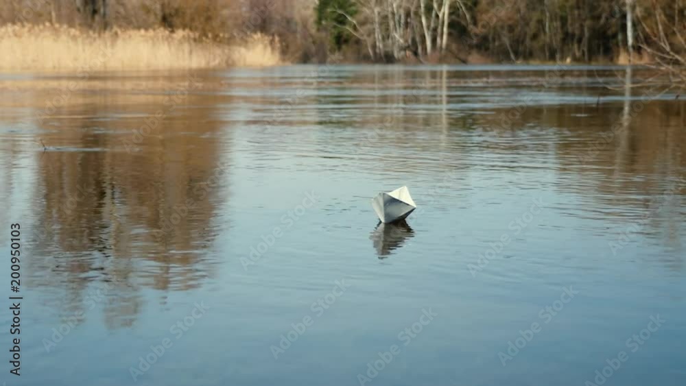 A paper boat is floating on the water. Origami boat floats away into the distance along the river