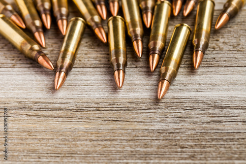 Rifle full metal jacket bullets on wooden background with copy space