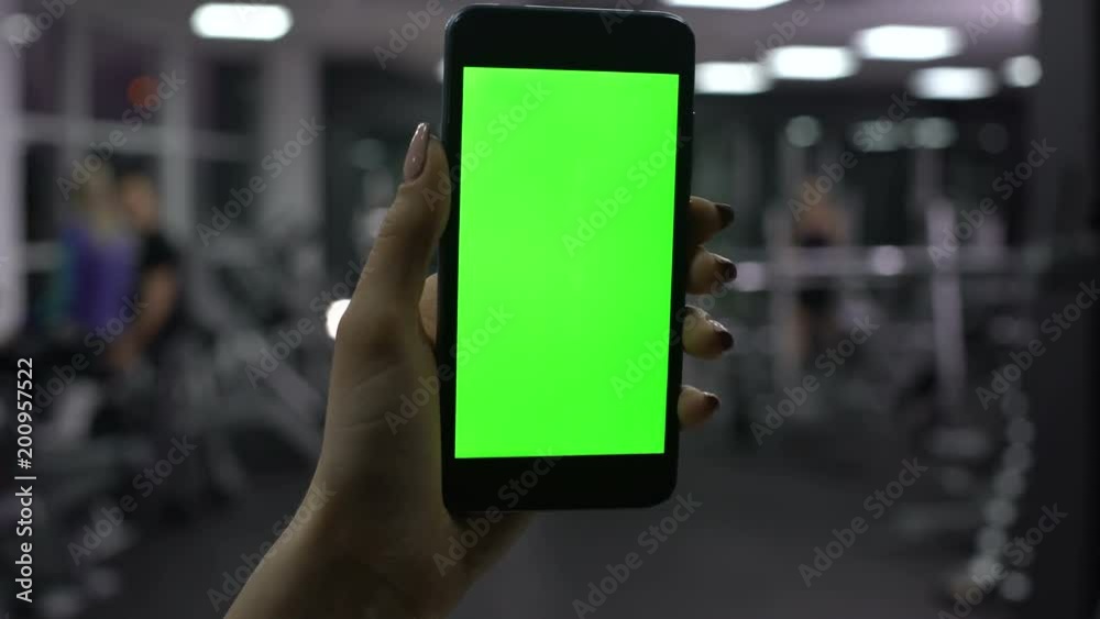 Woman checking amount of burned calories in smartphone application, green screen