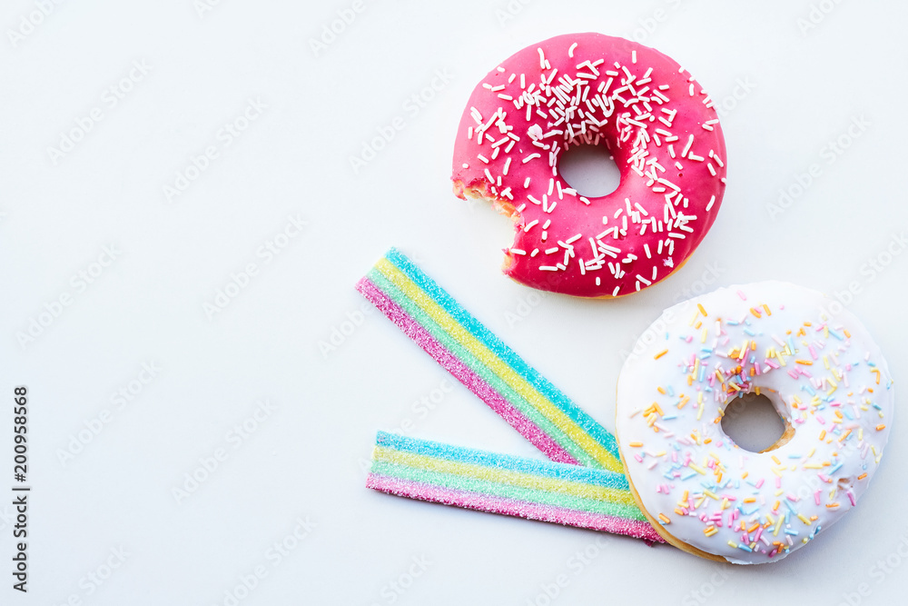 Bitten pink donut and jelly candies on the white background isolated. Copy space. Bitten pink donut and jelly candies on the white background isolated. Copy space.
