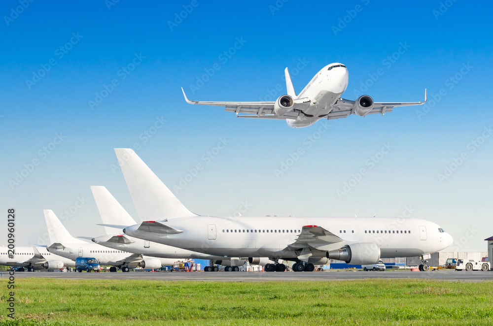 Row of passenger aircraft, airplane parked on service before departure. at the airport, other plane push back tow. One take off from the runway in the sky.