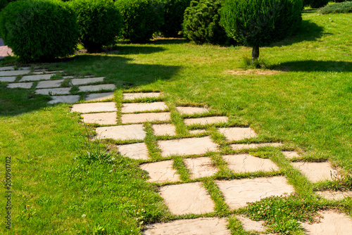 decorated stone paths among shrubs and flower beds in landscape design