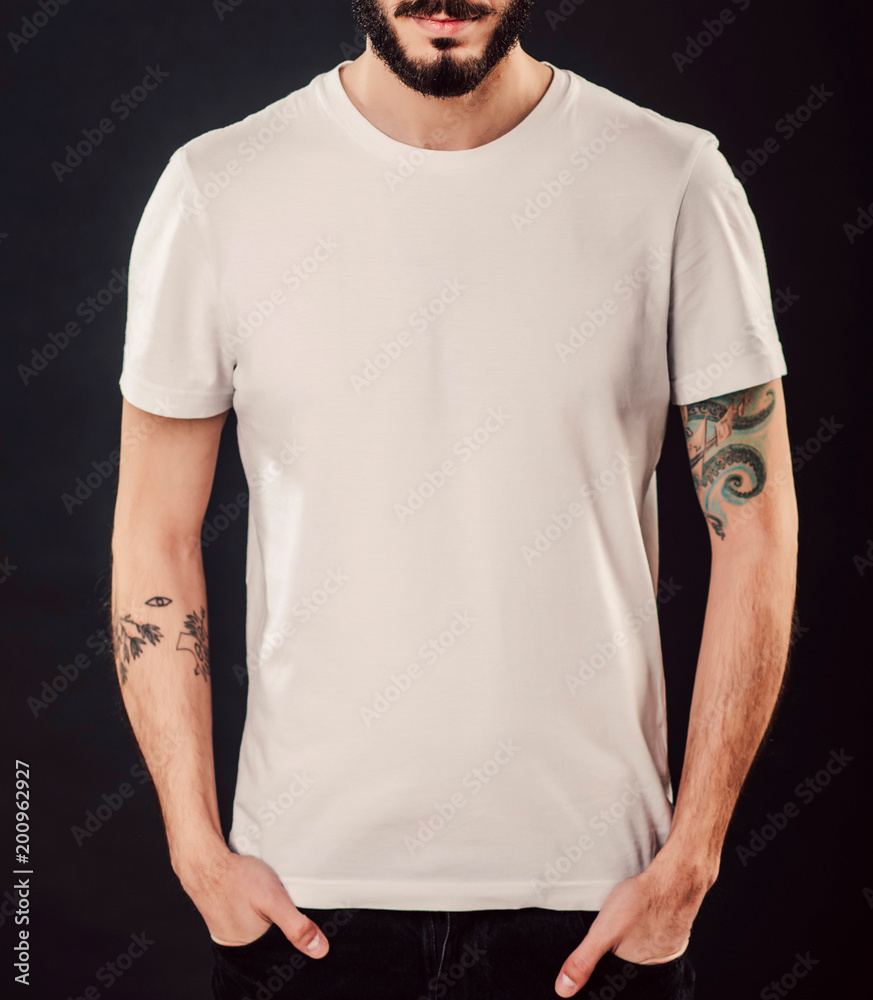 Young male body with blank white t-shirt on black background. Hipster with  beard and tattoo. Mock up Stock Photo
