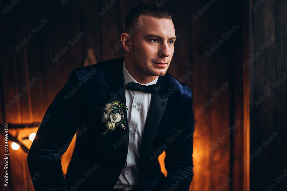 Fototapeta premium Portrait of young groom with wooden background