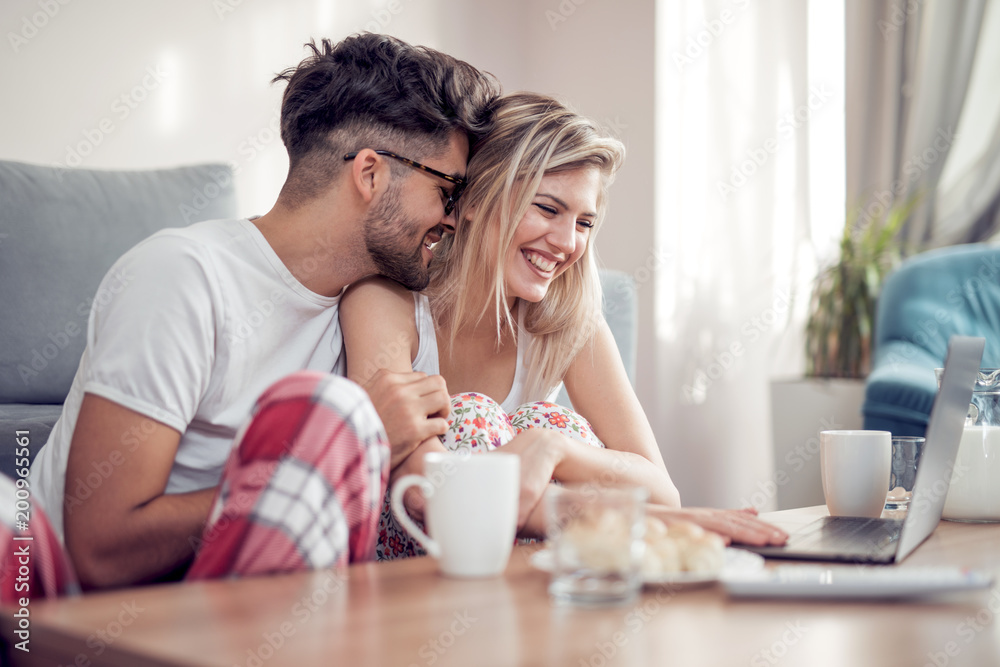 Couple using a laptop while having breakfast Couple using a laptop while having breakfast