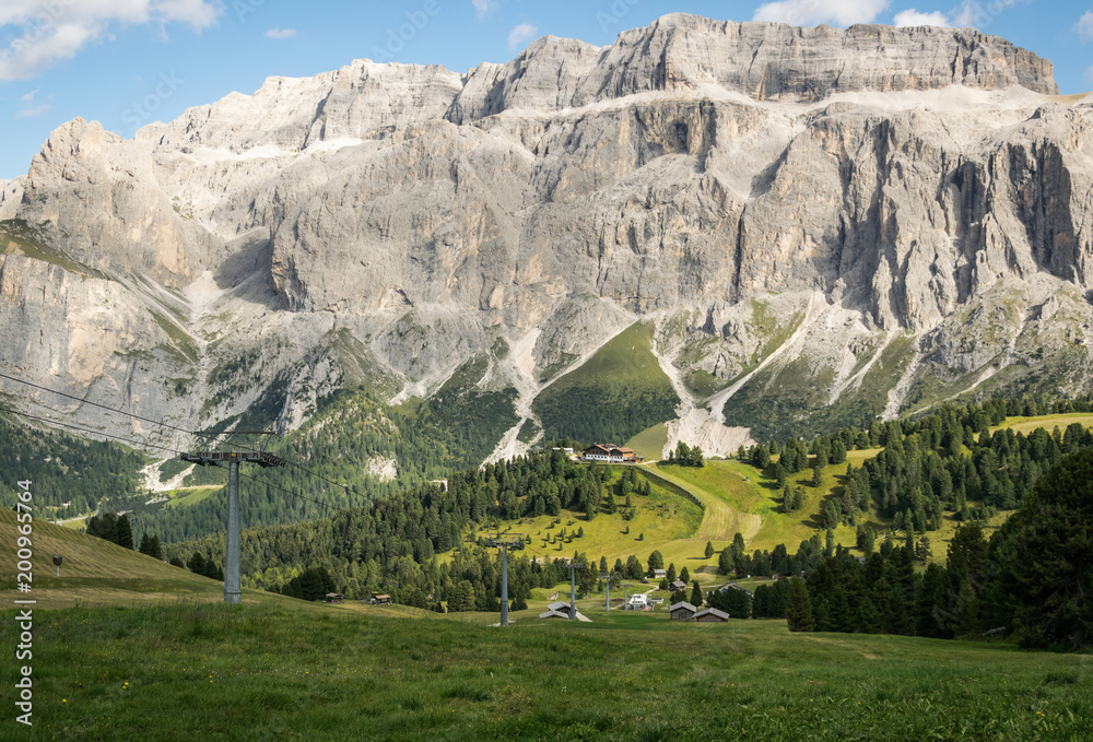 View to the Alps (Dolomites) mountains, ski-lifts and small house in the region Val Gardena in Italy while tracking in summer