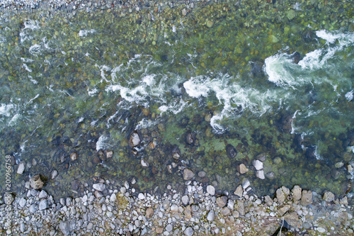Aerial shot of a flowing mountain river among the stones