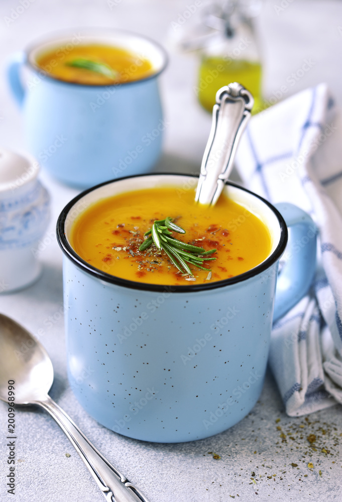 Two portions of pumpkin creamy soup in a blue emamel mugs. Two portions of pumpkin creamy soup in a blue emamel mugs.