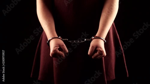 submissive woman wearing a purple dress in leather handcuffs on black background photo