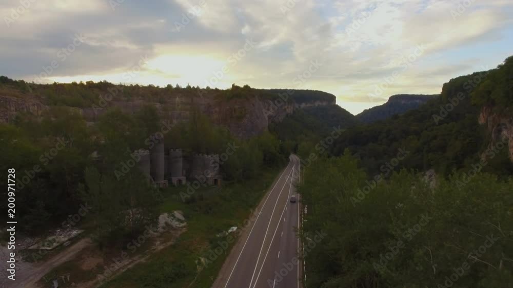 Flight over a rural landscape road following a car driving on it with lush green foliage, farming land. Aerial shot of a rural road with a car driving on it. 4k Flight over a rural landscape road following a car driving on it with lush green foliage, farming land. Aerial shot of a rural road with a car driving on it. 4k
