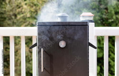 Close up of a smoker with fresh smoke coming out of barbeque cooker