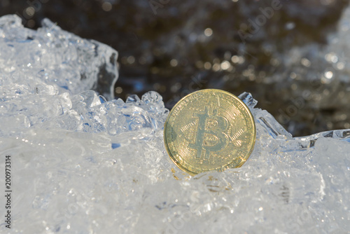 Physical golden bitcoin coin on ice
