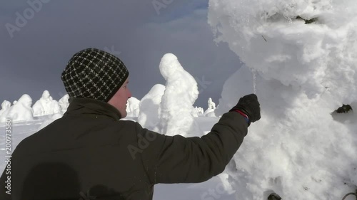 Man looking on icicles, in a snow covered forest, at a fjeld tunturi, in Riisitunturi national park, Lapland, Finland