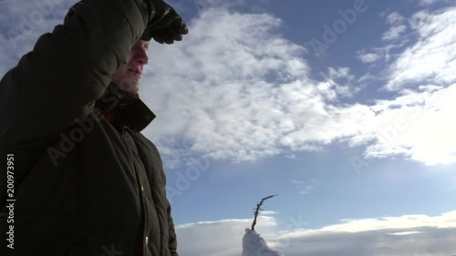 Man scoping on a snowy fjeld, Slow motion pan of a male looking at the view of snow covered trees, at a fjeld tunturi, in Riisitunturi national park, Lapland, Finland