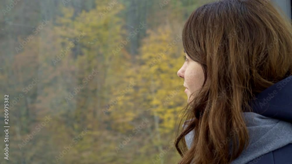 Young woman with dark hair is riding a cable car and looking at the forest under her. Handheld real time close up shot Young woman with dark hair is riding a cable car and looking at the forest under her. Handheld real time close up shot