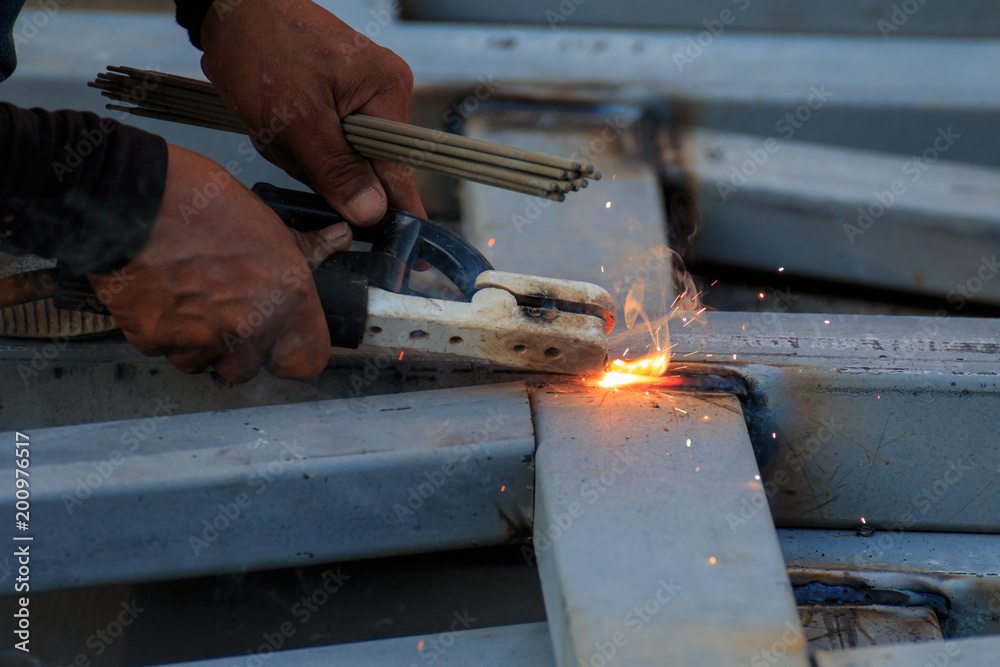 Asian worker making sparks while welding steel Asian worker making sparks while welding steel