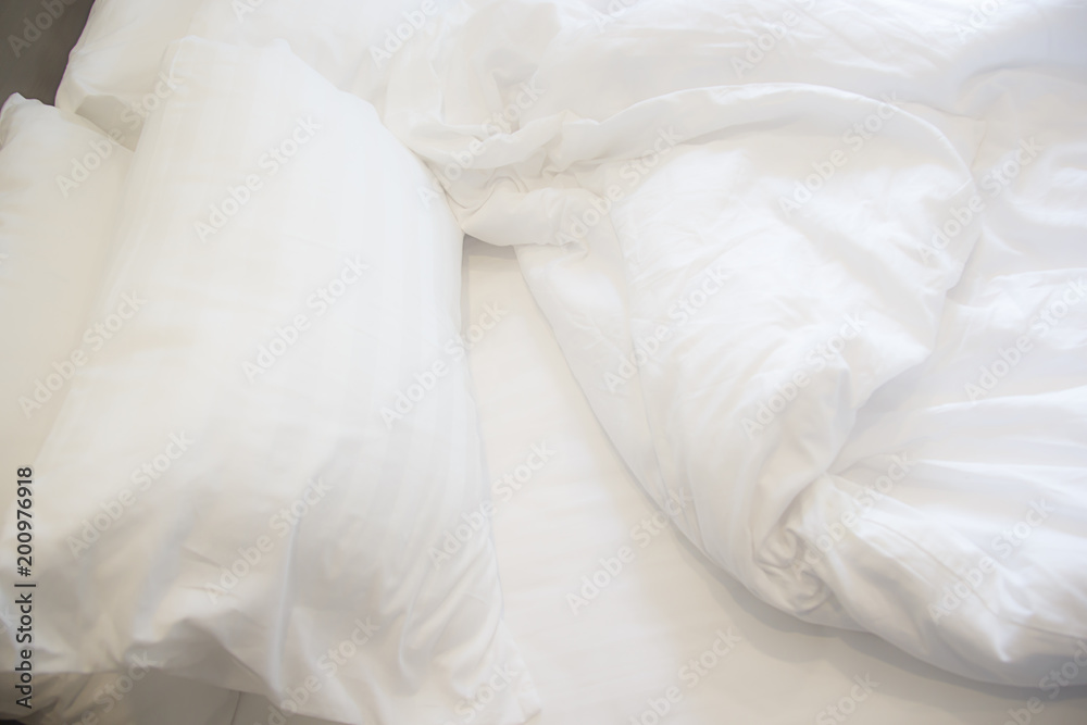 White pillow on the bed with blanket, bedding sheet and shadow soft focus