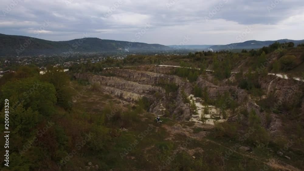 A young man on a moto bike rides along the cliff of the canyon. Aerial view 4k A young man on a moto bike rides along the cliff of the canyon. Aerial view 4k
