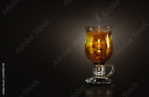 Glass with a hot herbal tea in a dark background
