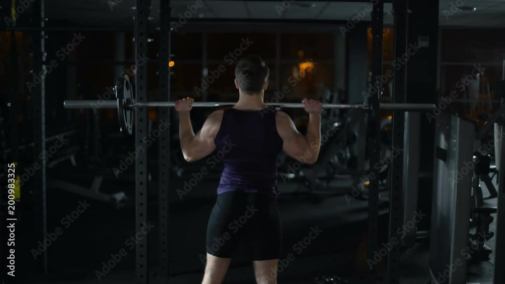 Bodybuilder doing exercise with barbell, training arms and shoulders muscles Bodybuilder doing exercise with barbell, training arms and shoulders muscles