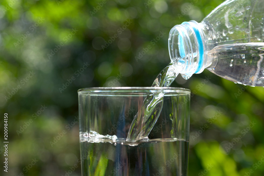 Pour water in the glass under green background. Pour water in the glass under green background.