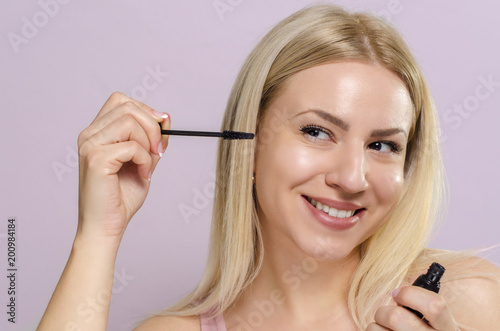 Closeup pretty woman applying mascara on eyelashes 