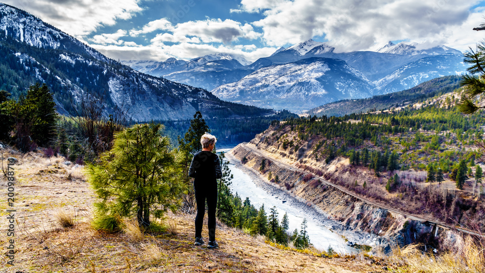 Senior Woman enjoying the view along the Fraser Canyon Route following the Thompson River as it flows through the snow covered mountains of the Coastal Mountain Range in western British Columbia