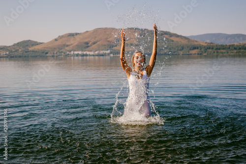girl in white dress bathes in the lake summer