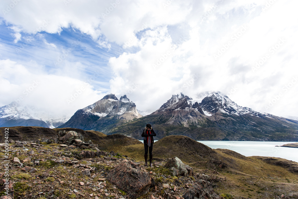 woman standing with arms wide open with Torres del Paine mountain range in the background