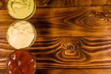 Different sauces in glass bowls on wooden table. Top view
