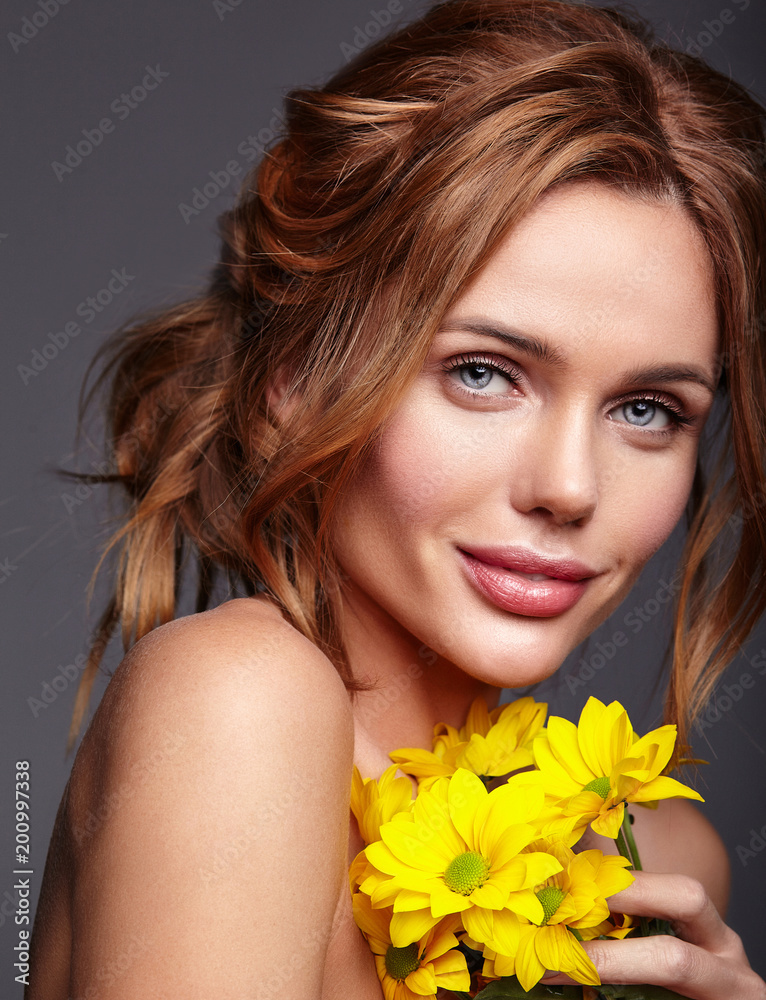Beauty fashion portrait of young blond woman model with natural makeup and perfect skin with bright yellow chrysanthemum flower posing in studio Beauty fashion portrait of young blond woman model with natural makeup and perfect skin with bright yellow chrysanthemum flower posing in studio