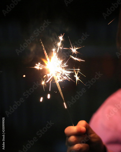 Close-up child hand holding fire sparklers on the festival.