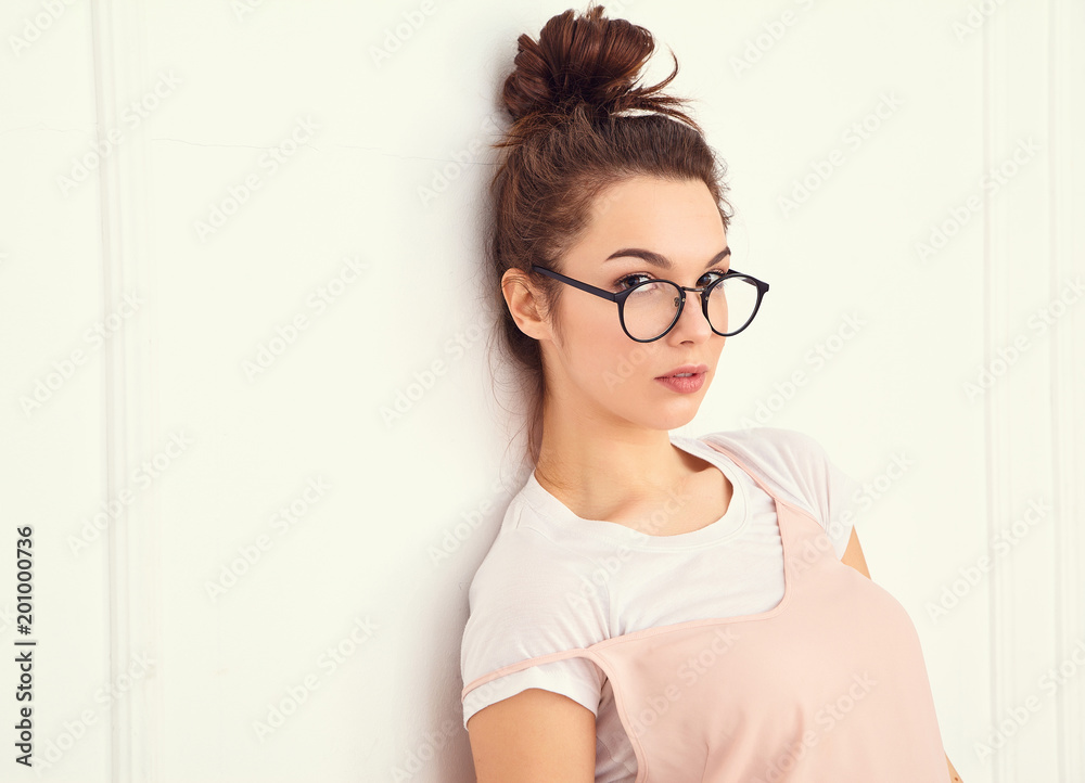 Portrait of young beautiful brunette woman girl model with nude makeup in colorful summer pink hipster clothes posing near wall. Going crazy and looking happily in camera