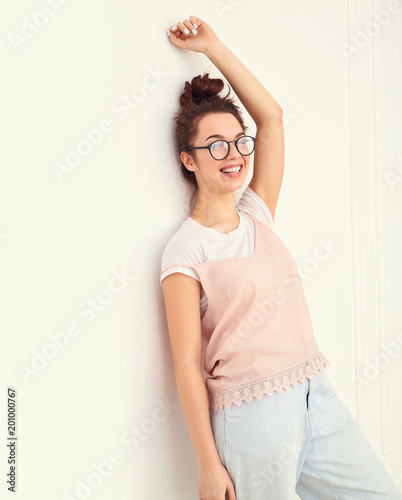 Portrait of young beautiful brunette woman girl model with nude makeup in colorful summer pink hipster clothes posing near wall. Going crazy and looking happily in camera