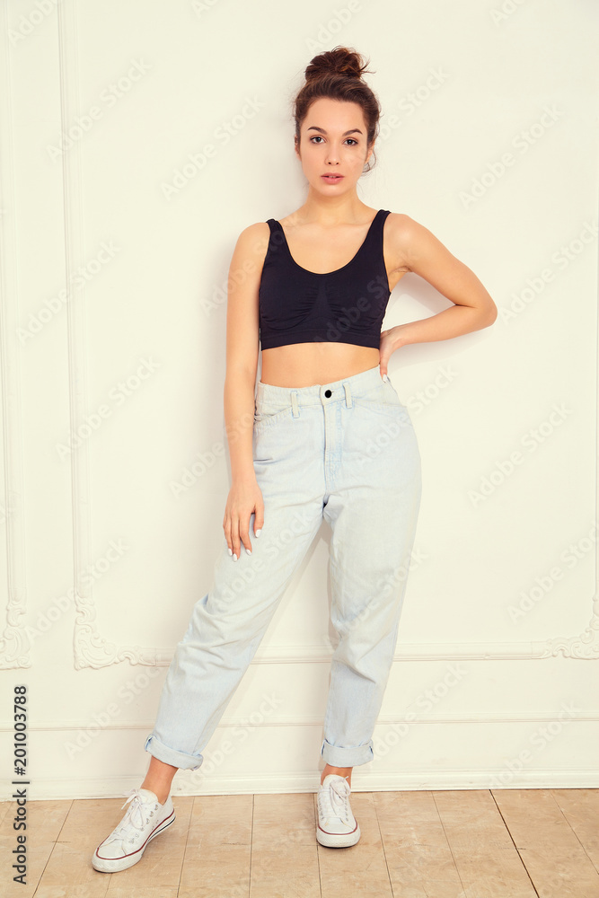 Portrait of young beautiful brunette woman girl model with nude makeup in summer T-shirt top and jeans hipster clothes posing near wall. Going crazy Portrait of young beautiful brunette woman girl model with nude makeup in summer T-shirt top and jeans hipster clothes posing near wall. Going crazy
