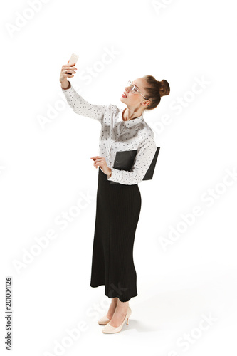 Full length portrait of a smiling female teacher holding a folder isolated against white background